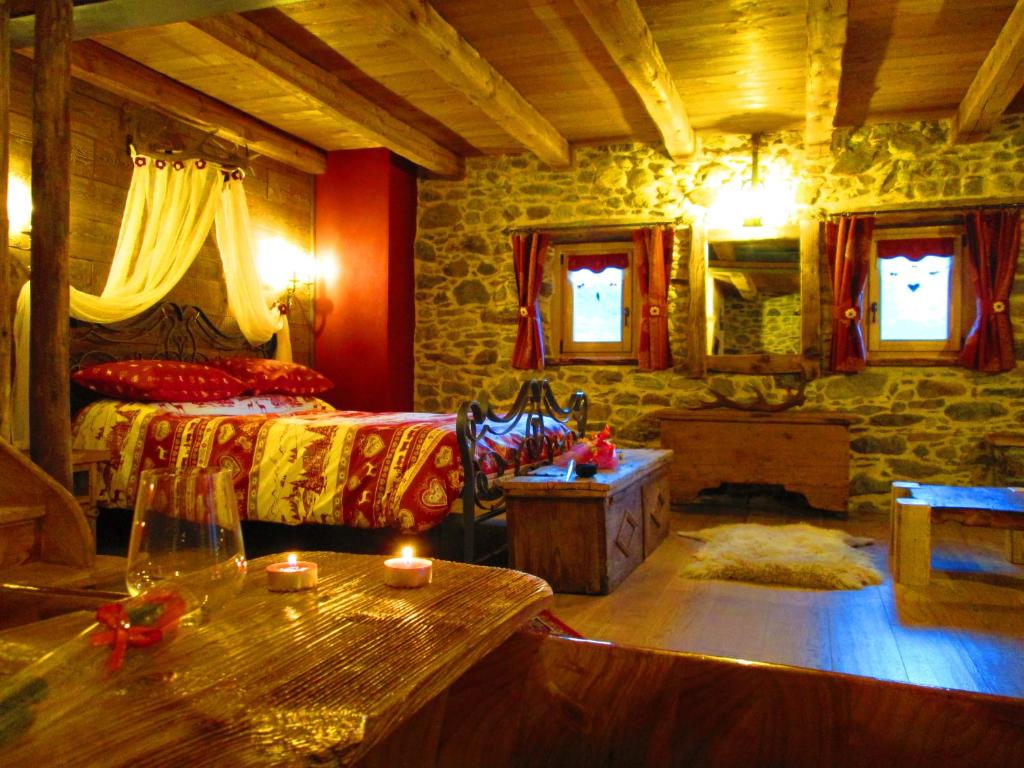 1 dormitorio con 1 cama y 1 mesa con velas en Chalet Cuore Selvatico, en Monno