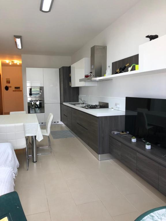 una cucina con tavolo da pranzo e una cucina con armadietti bianchi di Modern Apartment with sea view a Mellieħa