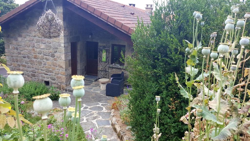 una casa de piedra con un jardín delante de ella en La Croisée des Fleurs, en Lapte