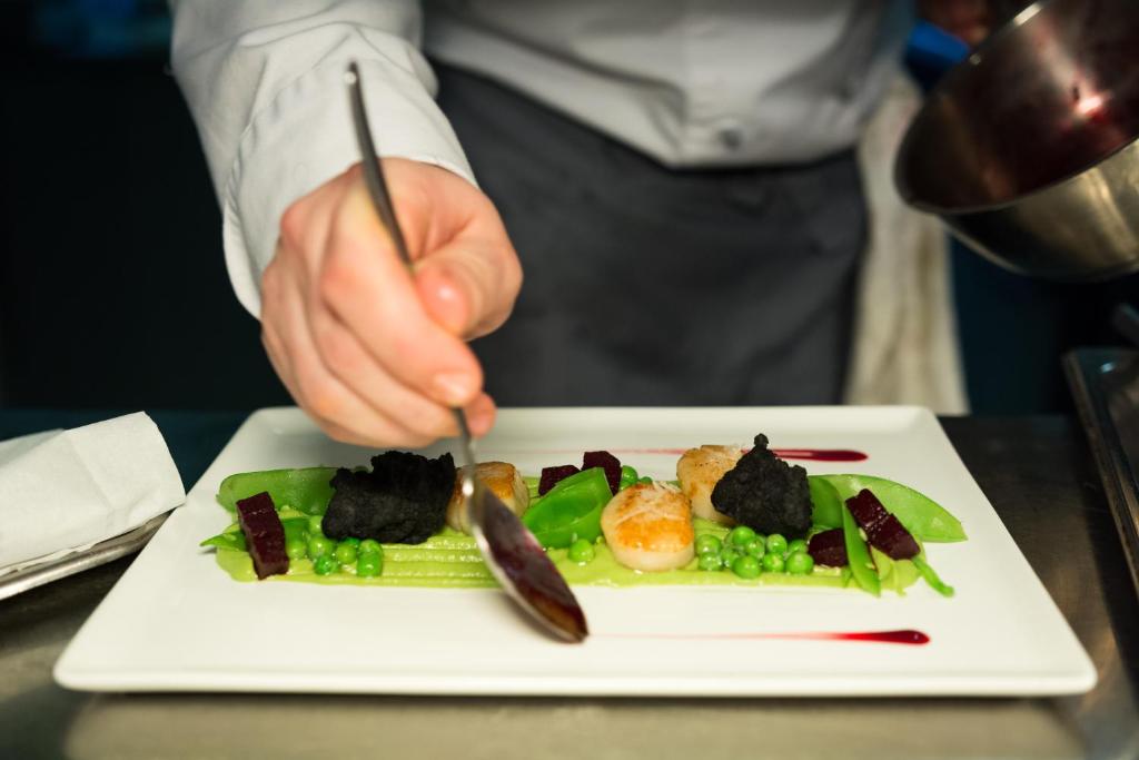 a person holding a knife and a plate of food at Alchymist Grand Hotel and Spa - Preferred Hotels & Resorts in Prague