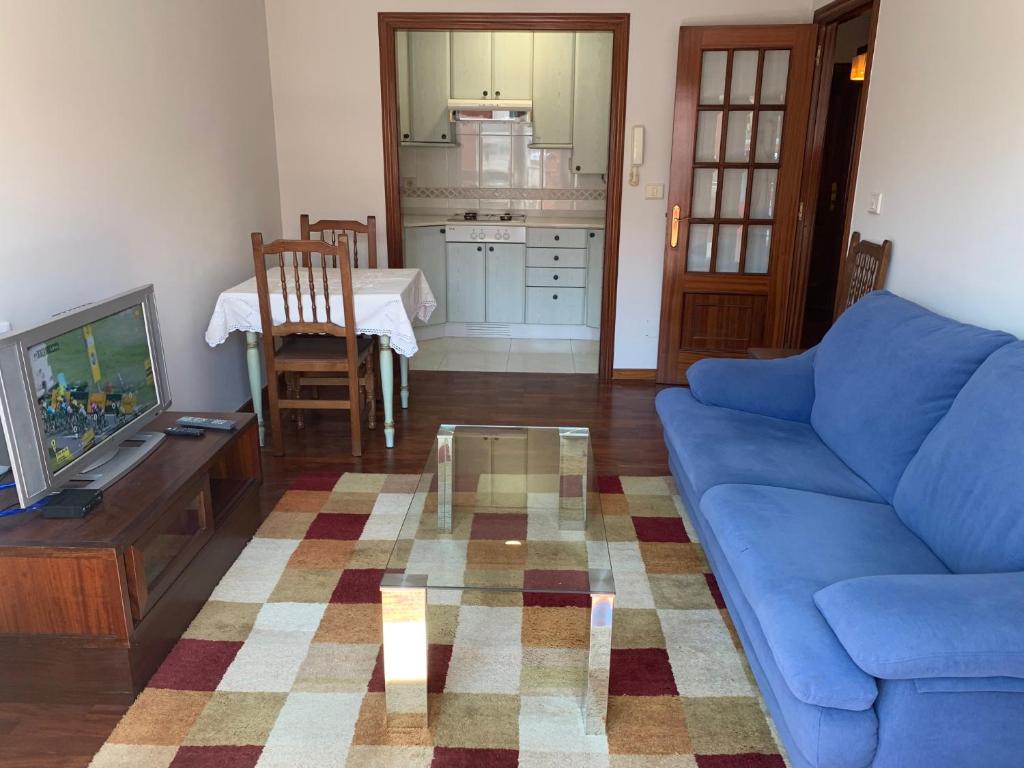 a living room with a blue couch and a tv at Apartamento privado a 15 minutos de Santiago y 15 de las playas de Noia y Barbanza in Rois