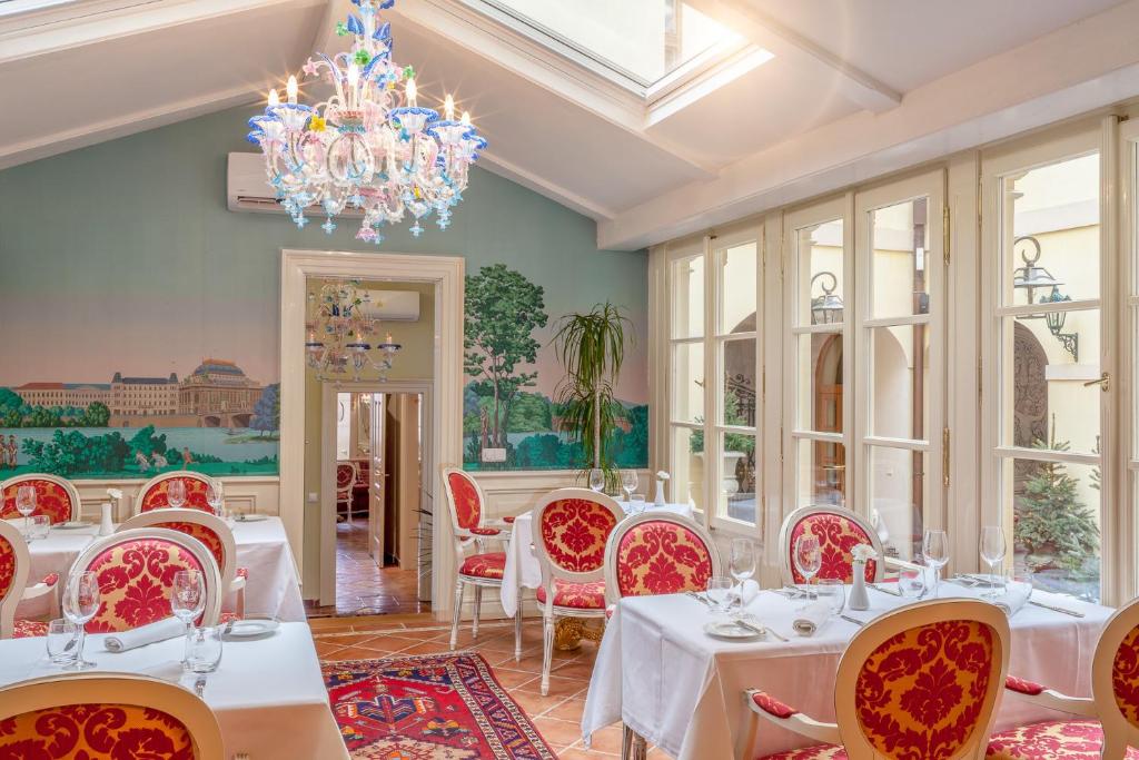 a dining room with white tables and chairs and a chandelier at Alchymist Grand Hotel and Spa - Preferred Hotels & Resorts in Prague