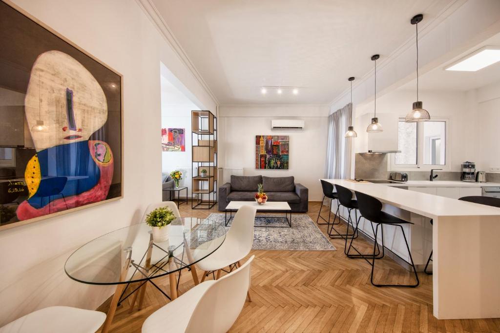 eine Küche und ein Wohnzimmer mit einem Glastisch und Stühlen in der Unterkunft Kolonaki Square Executive Apartment in Athen