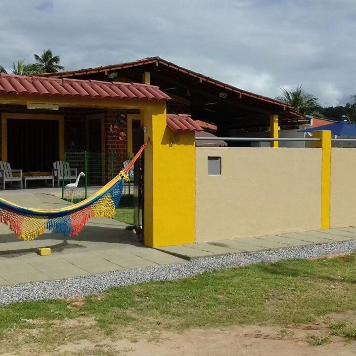 a yellow house with a hammock outside of it at Casa na Praia em Maceió apenas a 120 mts do Mar in Maceió