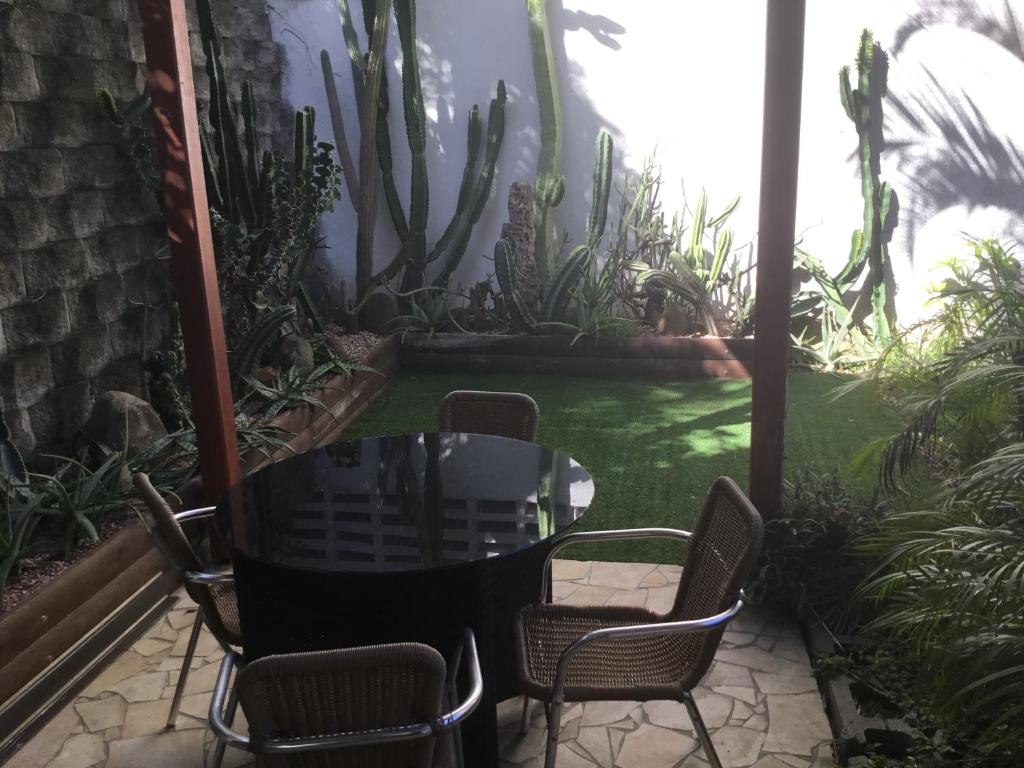 a patio with chairs and a table and a garden at Résidence les cactus in Noumea