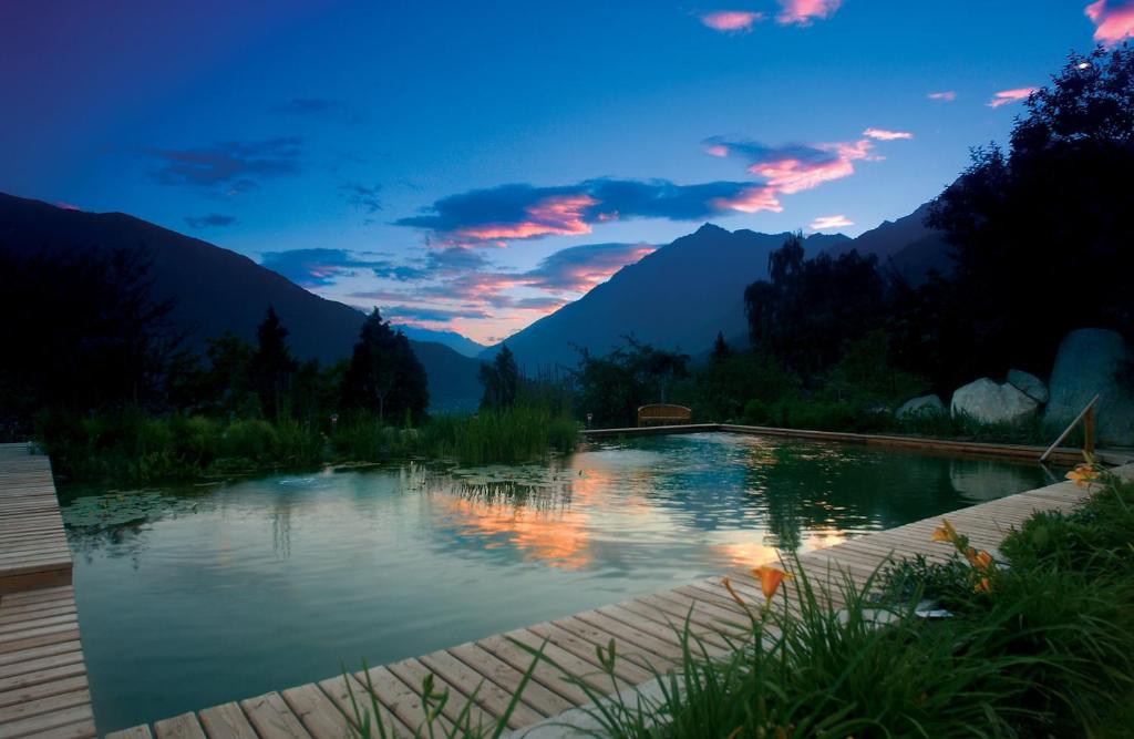 un bassin d'eau avec des montagnes en arrière-plan dans l'établissement Marini's giardino Hotel, à Tirolo