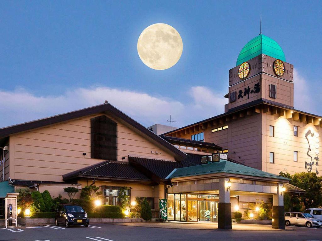 a large building with a clock tower with a moon at Awara Onsen hot spring Koubou Gurabaatei in Awara