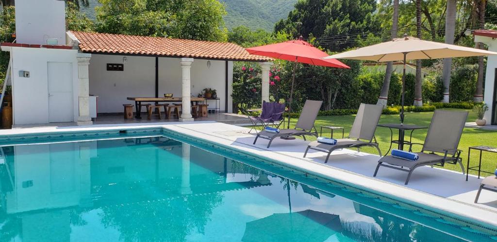 einen Pool mit Stühlen und Sonnenschirmen neben einem Haus in der Unterkunft Casa cerca de las Estacas in Ticumán