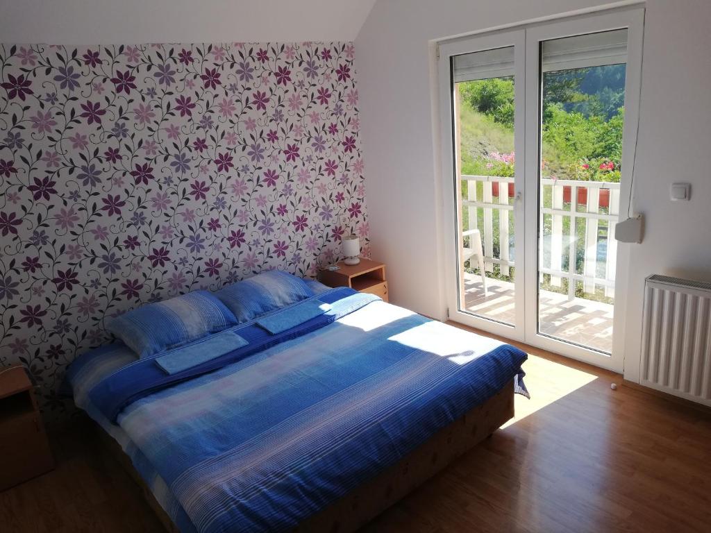 a bedroom with a bed with blue sheets and floral wallpaper at Farm Stay Cvijovic in Mokra Gora