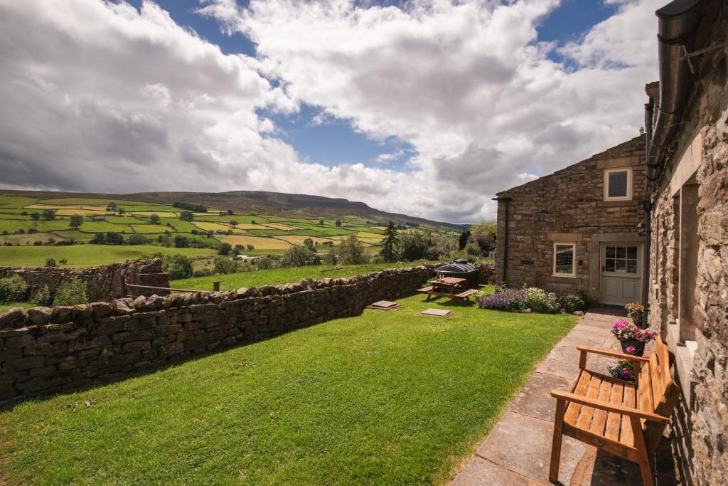un edificio de piedra con un banco junto a una pared en Crow Hall - Luxury Holiday Accommodation, en Reeth