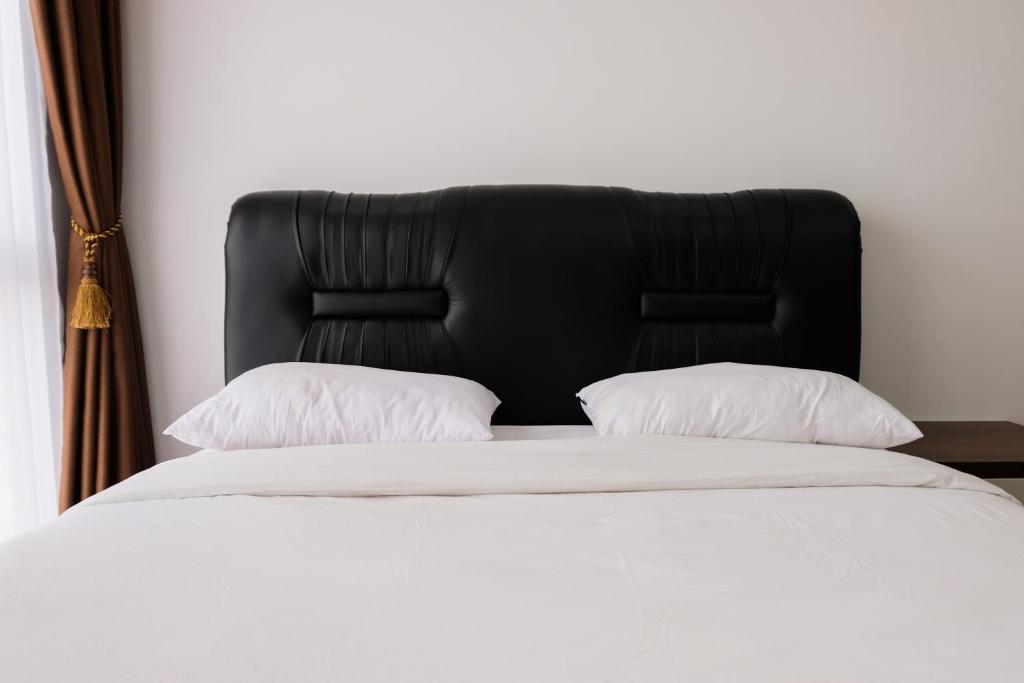 a bed with a black headboard and two pillows at 1BR Apartment at M-Town Residence near Summarecon Mall Serpong By Travelio in Tangerang