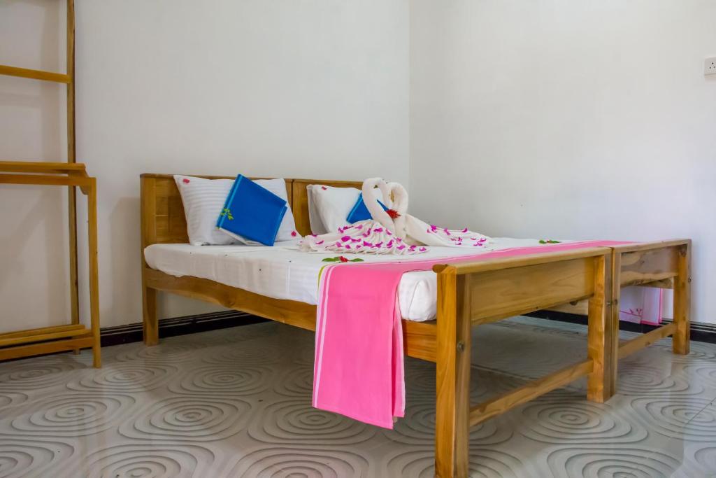 a small bed with a pink blanket on it at Beach Lagoon Parans in Arugam Bay