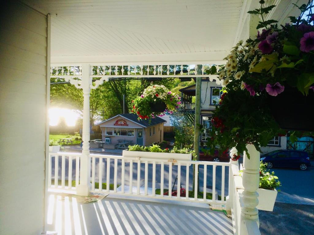 a white porch with a white fence and flowers at Le « Lake View » de la Suite North Hatley in North Hatley