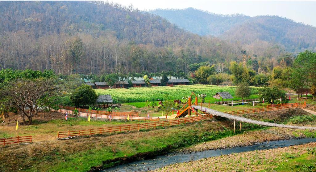 un ponte di legno su un fiume in un campo di Karen Eco Lodge a Chiang Mai