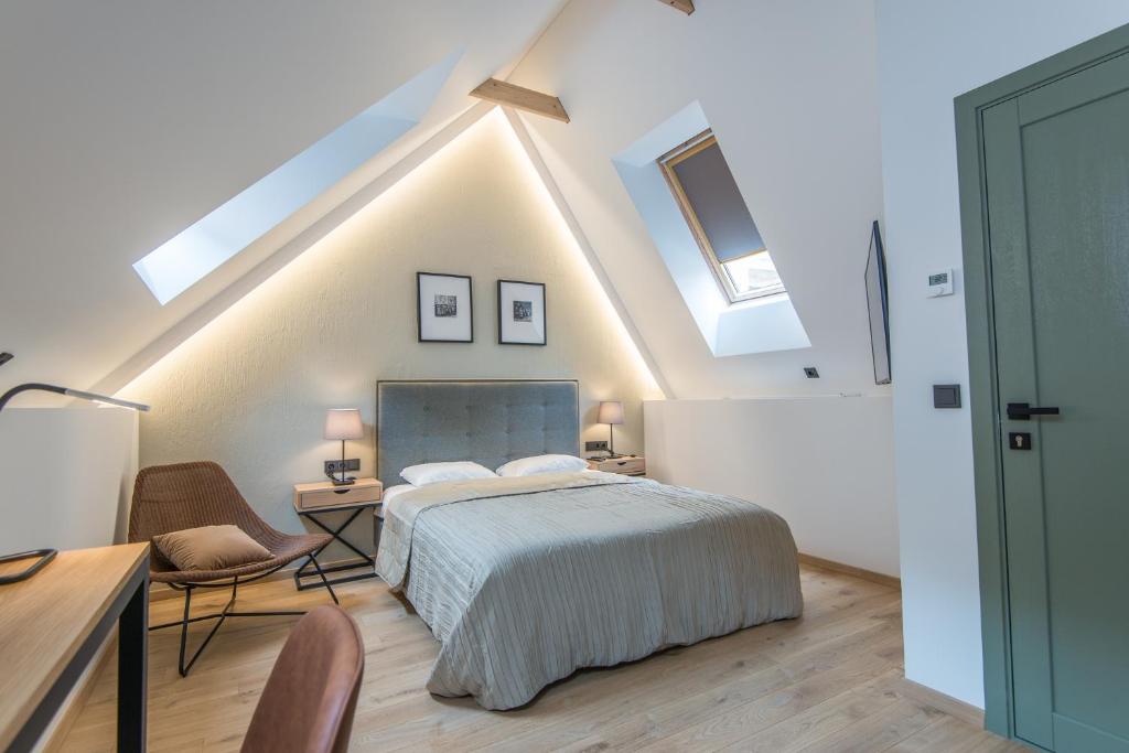 a bedroom with a bed and a desk and some skylights at COME2rest - Stikliu 20 in Vilnius