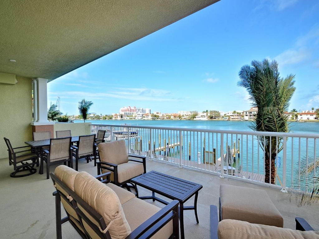 a balcony with tables and chairs and a view of the water at Sandpiper's Cove 203 Luxury Waterfront 3 Bedroom 2 Bath Condo 23130 in Clearwater Beach