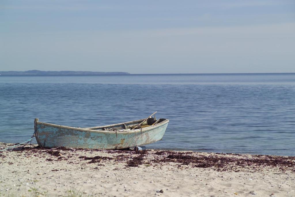 um barco sentado numa praia junto à água em Norsminde Kro em Odder
