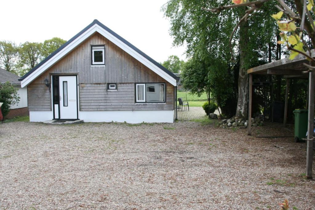 um celeiro com uma porta branca e um estaleiro de cascalho em vakantiewoning grensgebied Groningen/Drenthe/Friesland em Zevenhuizen