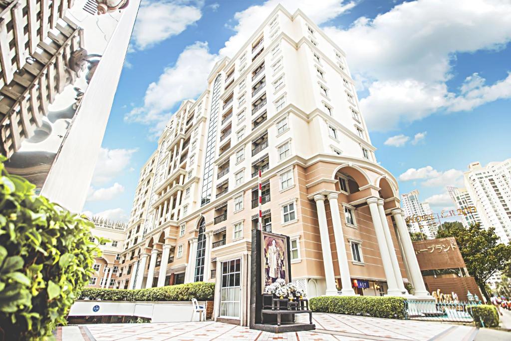 a large white building on a city street at Hope Land Hotel Sukhumvit 24 in Bangkok