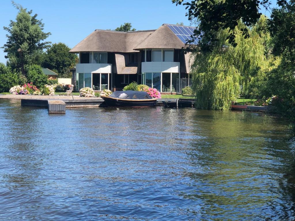 ein Haus auf dem Wasser mit einem Boot darin in der Unterkunft Villa Braas in Breukeleveen