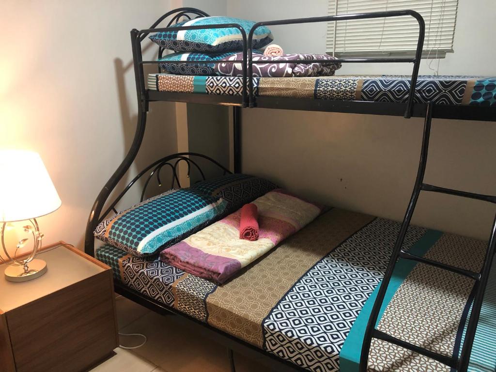 1 Schlafzimmer mit 2 Etagenbetten und einer Lampe in der Unterkunft Baguio Central Apartment by Goshenland in Baguio City