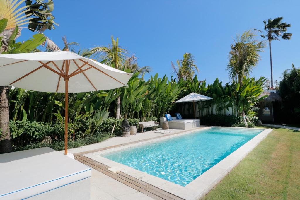 - un parasol à côté d'une piscine avec une cour dans l'établissement Amazing 3 Bedrooms Villa Canggu, à Canggu