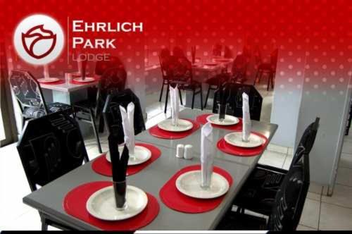 a table in a restaurant with red and white plates and chairs at Ehrlichpark Lodge self catering and spa in Bloemfontein