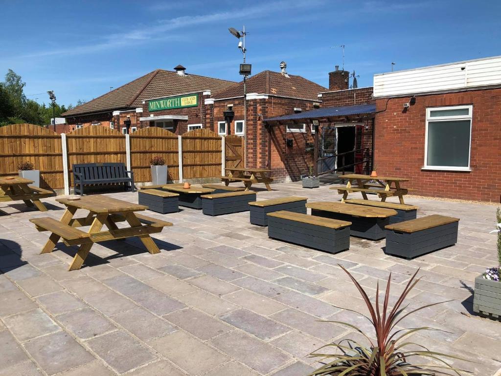 a patio with picnic tables and benches in front of a building at Minworth Lodge in Minworth