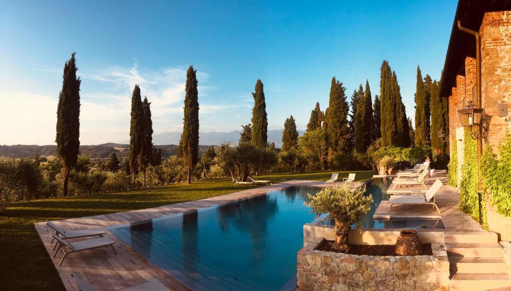 uma piscina num jardim com árvores ao fundo em Villa Barberino em Meleto