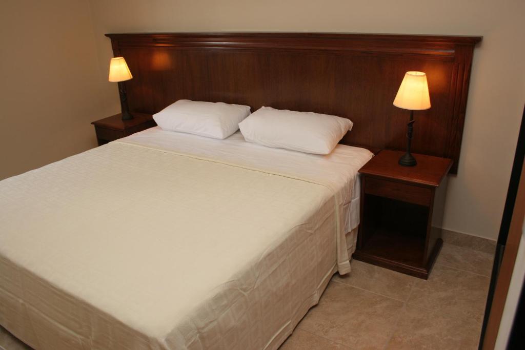 1 dormitorio con 1 cama blanca grande y cabecero de madera en Inter Apart Hotel en Salta
