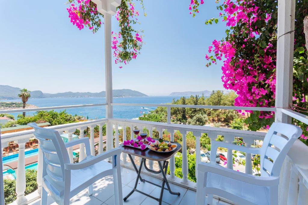 a balcony with chairs and a table with flowers at Hotel Koza in Kaş