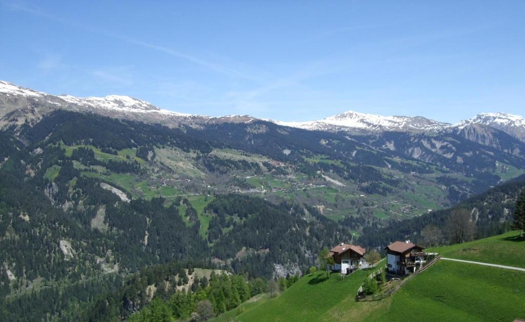 een huis op een heuvel met bergen op de achtergrond bij Aegerta Alte Schreinerei in Tschiertschen
