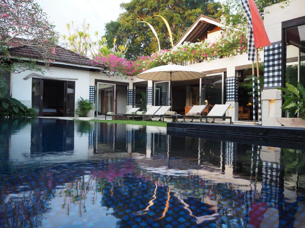 a swimming pool in front of a house at Pronoia Beach Resort in Jimbaran