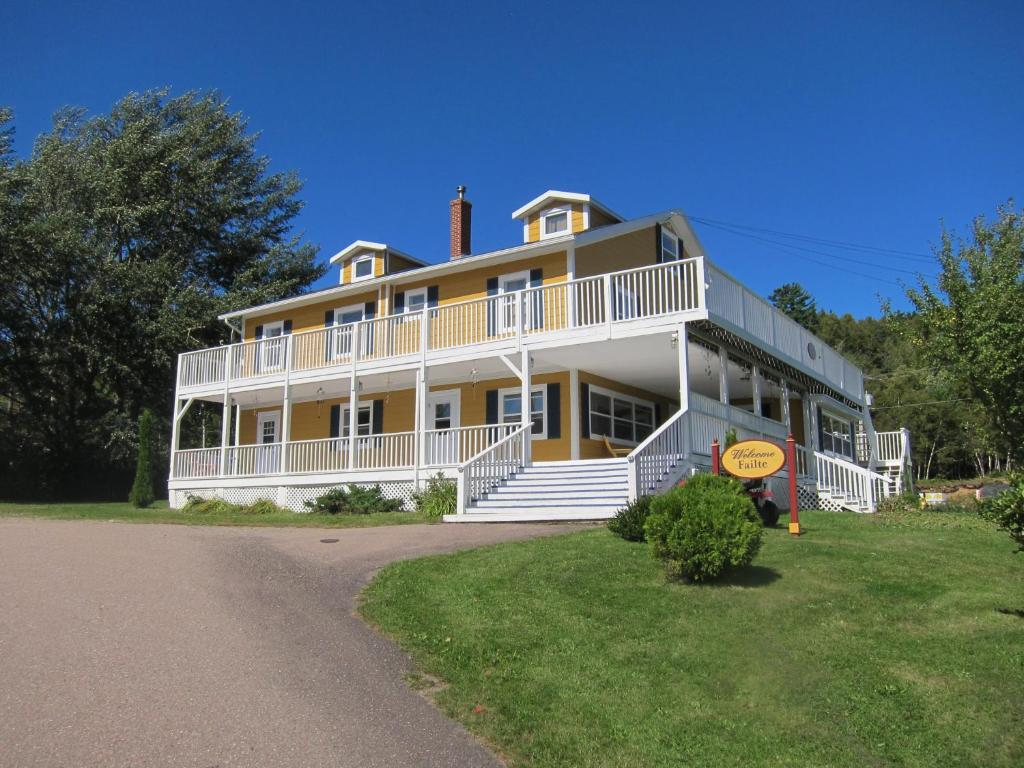 Casa grande de color blanco y amarillo con porche en The Island Inn, en Ingonish