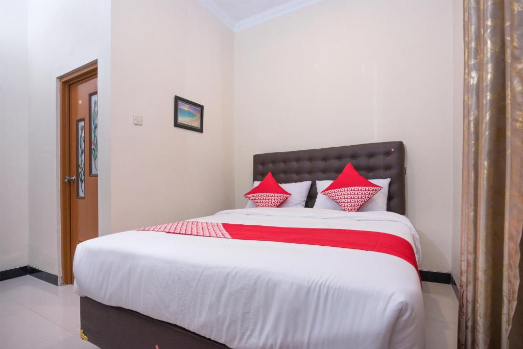 1 dormitorio con 1 cama grande con almohadas rojas en OYO 1226 Al Abror Homestay en Yogyakarta