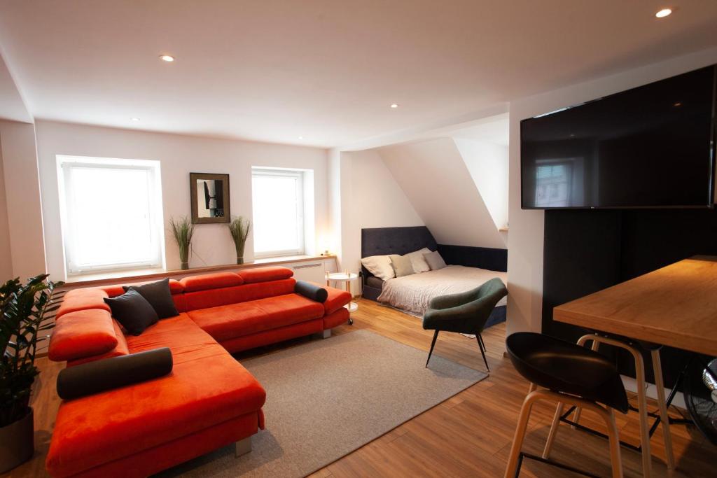 a living room with a red couch and a bed at Apartament Rynek N°21 in Gliwice