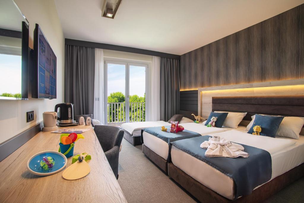 una camera d'albergo con due letti e una televisione di Hotel Haliaetum - San Simon Resort a Izola