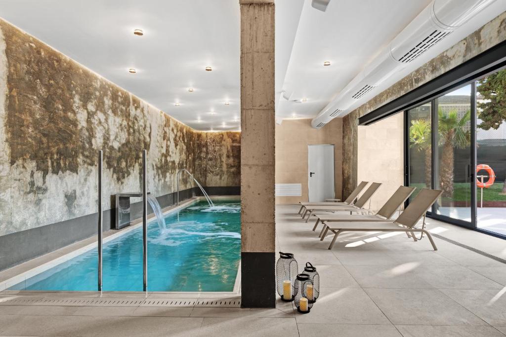 a swimming pool with lounge chairs in a room with a wall at Hotel Paradiso Garden in Playa de Palma