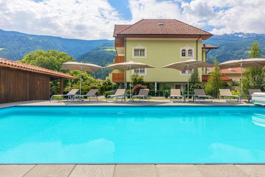 uma piscina num hotel com cadeiras e guarda-sóis em Wohlfühlhotel Mei Auszeit em Plaus