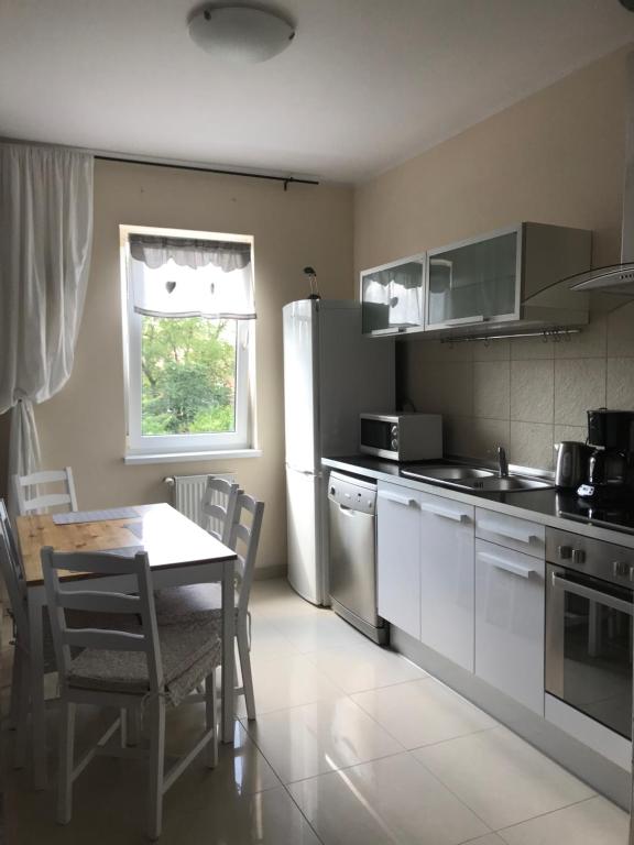 a kitchen with a table and a white refrigerator at Apartament Sloneczny Taras in Olsztyn