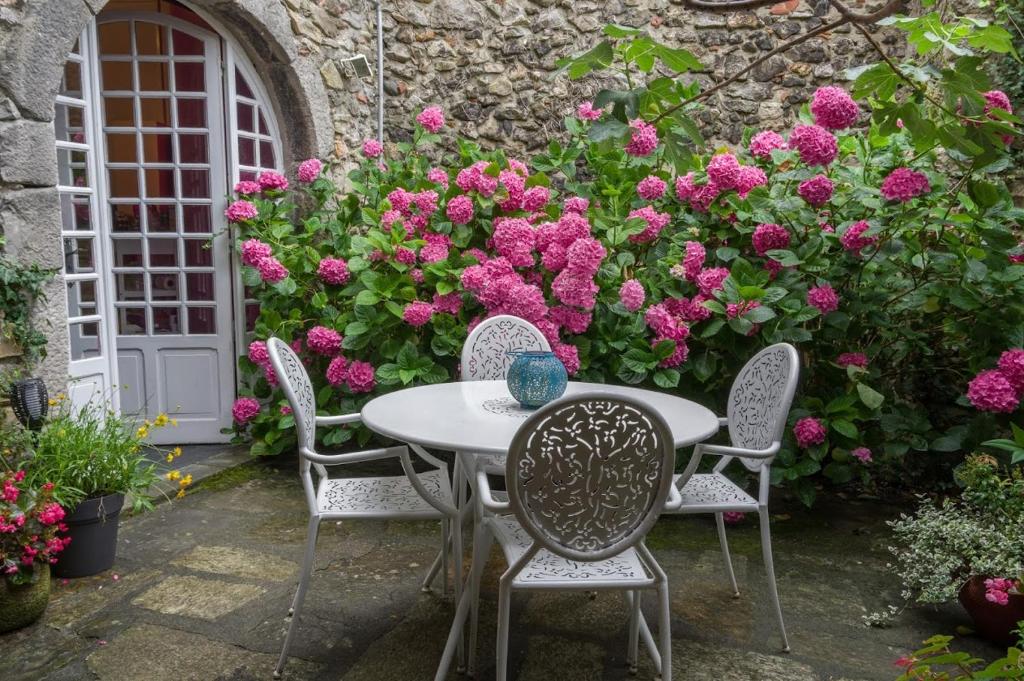a table and chairs in a garden with pink flowers at la Fadette in Saint-Lizier
