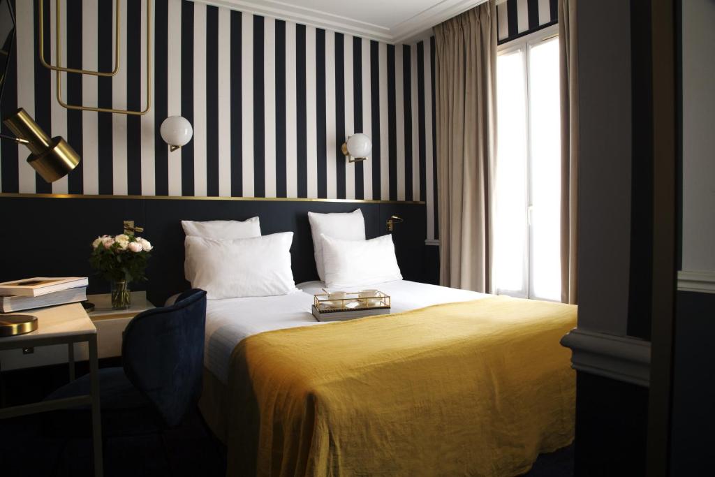 a bedroom with a bed with a desk and a window at Hôtel Léna in Paris