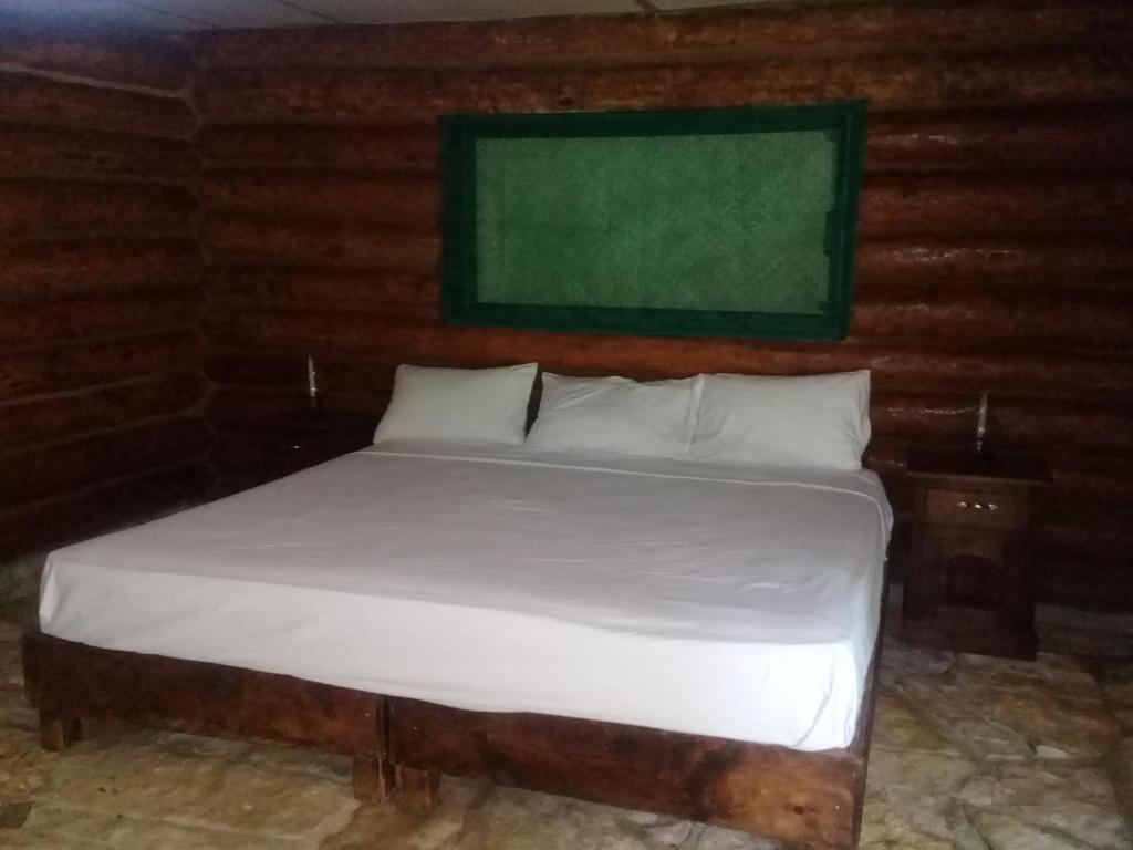 een bed in een kamer met een groen bord aan de muur bij Sierraverde Cabins Cabaa la Palma in Tamasopo