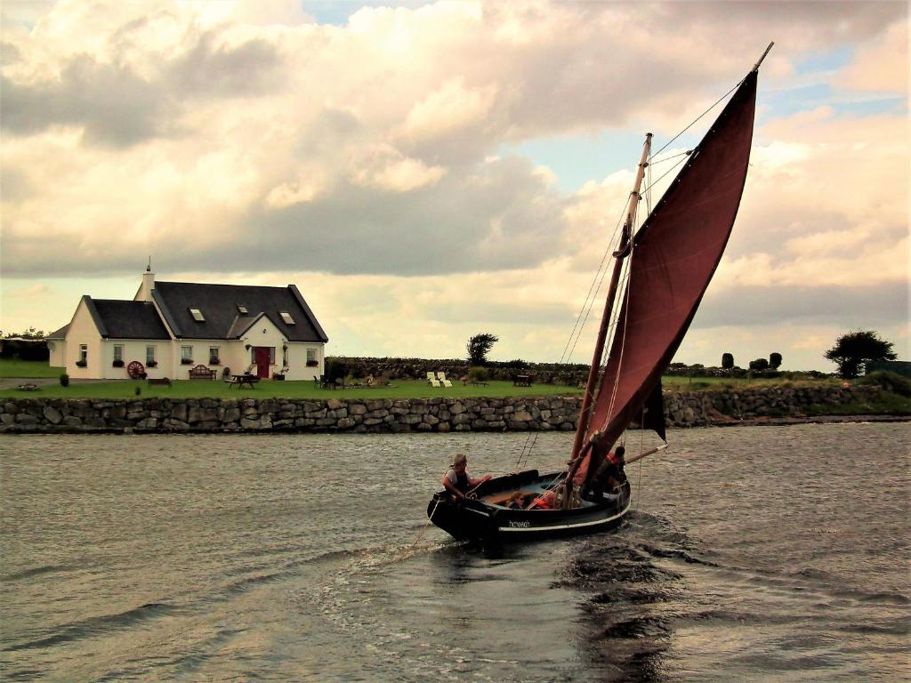 a man riding a small sail boat in the water at Breacan Cottage B&B in Kinvara