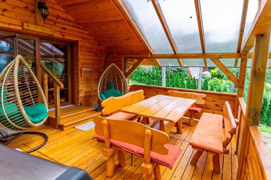 a wooden cabin with a table and chairs on a deck at Domek Brenna in Brenna