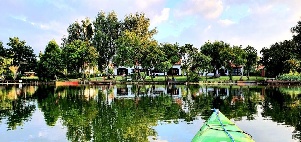 un kayak verde en un lago con árboles y casas en Mazurski Dom nad Jeziorem en Pasym