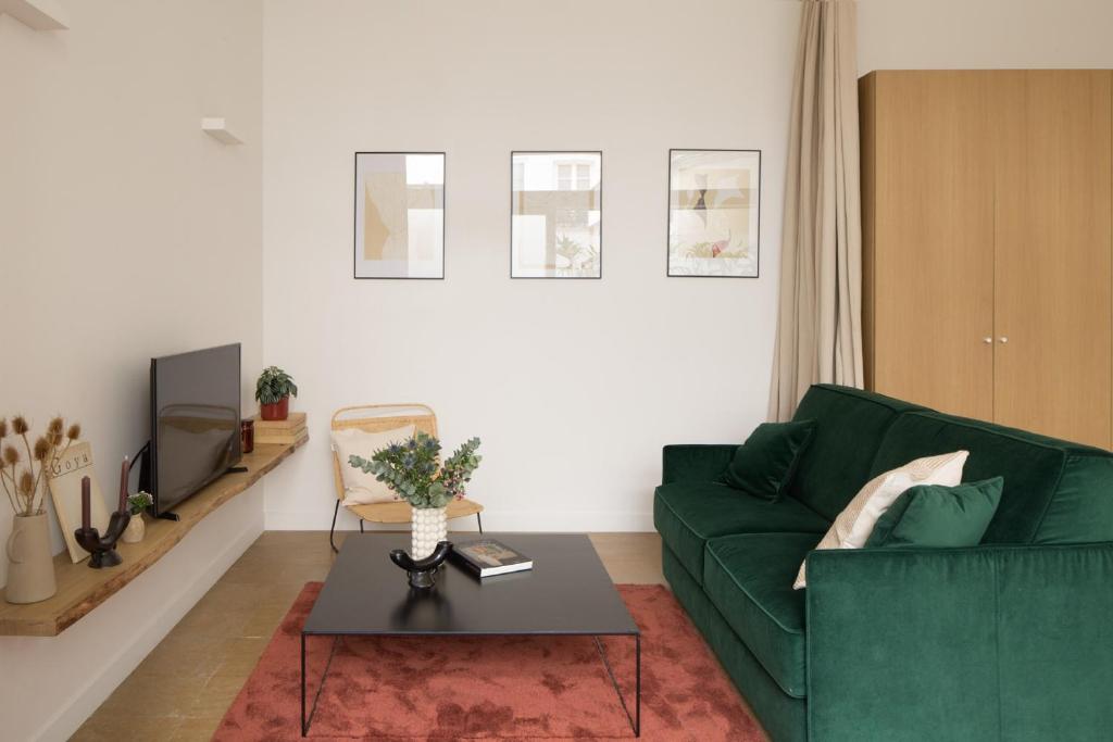 a living room with a green couch and a table at Joie Paris St Germain-des-Prés - Bon Marché in Paris