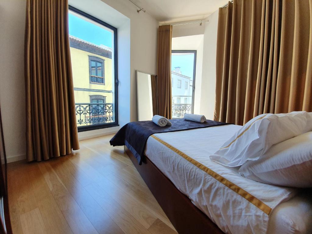 um quarto com uma cama e uma grande janela em Sophia em Ponta Delgada