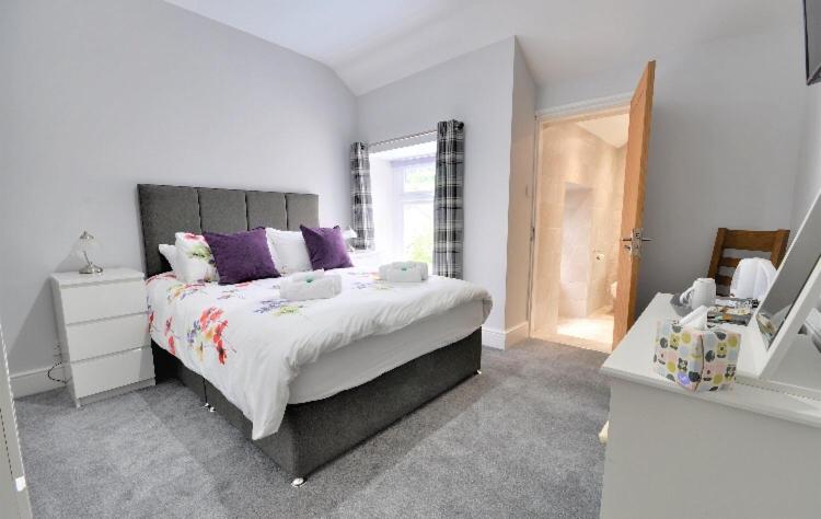 a bedroom with a large bed with purple pillows at Cae Garw B&B in Betws-y-coed