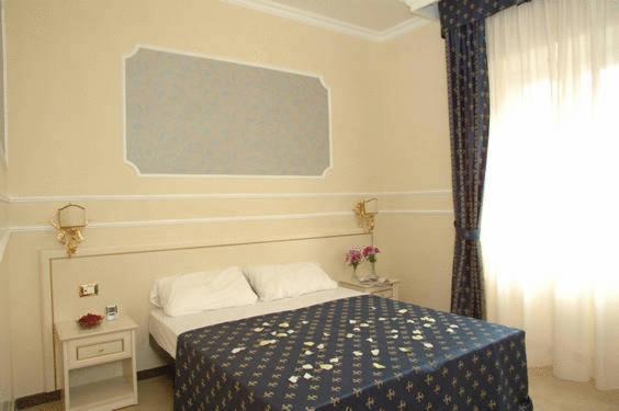 a bedroom with a bed with a blue blanket and a window at Cesar Palace Guesthouse in Rome